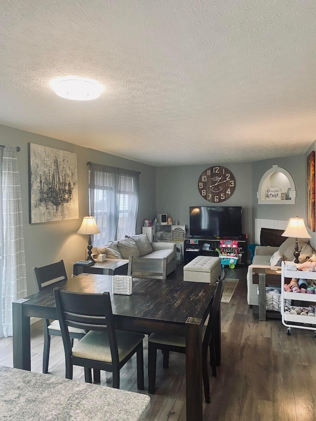 dining room with dark wood-type flooring and a textured ceiling