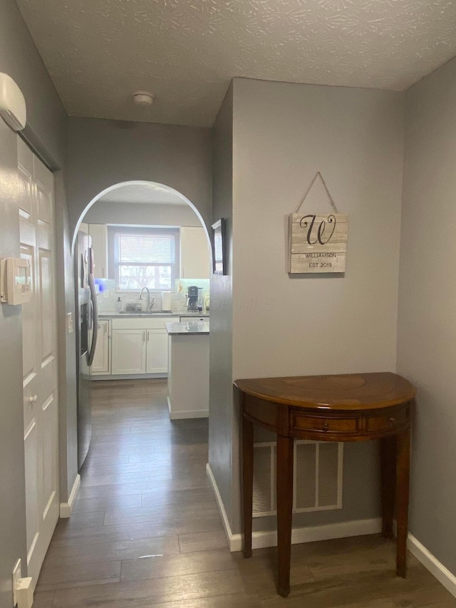 hallway with dark hardwood / wood-style floors, sink, and a textured ceiling