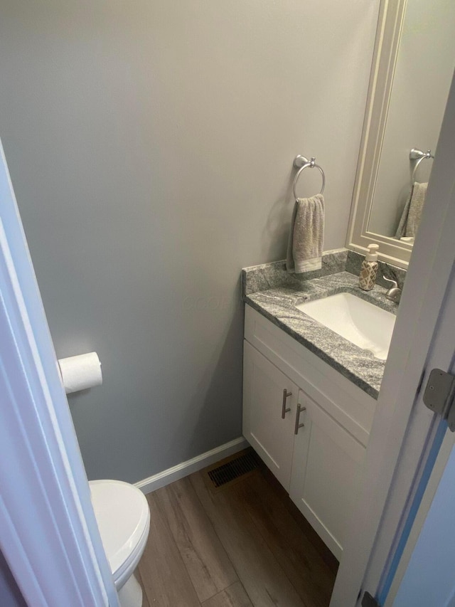 bathroom with hardwood / wood-style flooring, vanity, and toilet