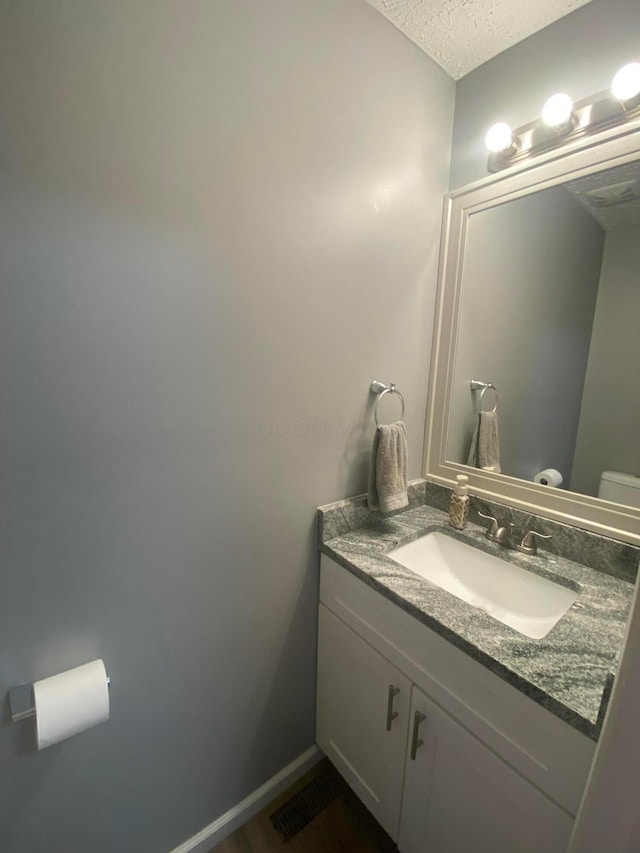 bathroom with vanity, a textured ceiling, and toilet