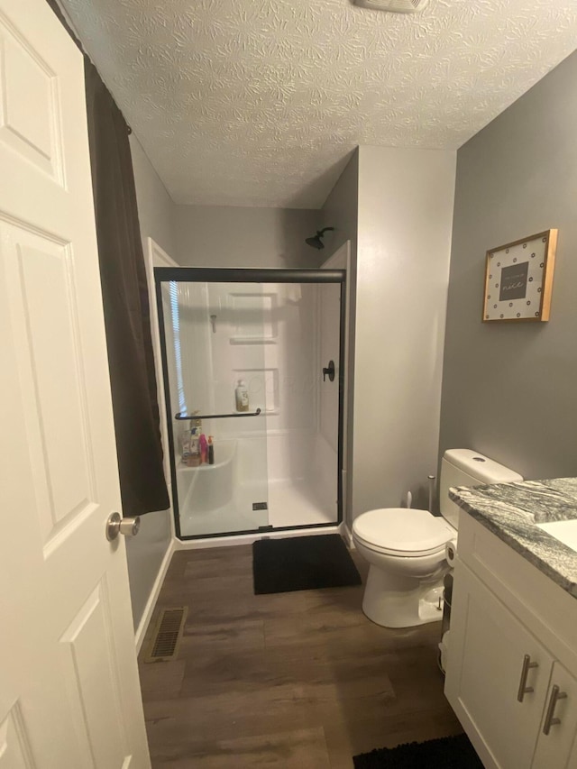 bathroom featuring an enclosed shower, vanity, wood-type flooring, and a textured ceiling