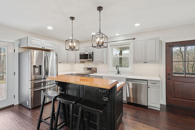 kitchen featuring sink, white cabinetry, wooden counters, a center island, and appliances with stainless steel finishes