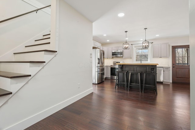 kitchen featuring a breakfast bar, decorative light fixtures, appliances with stainless steel finishes, dark hardwood / wood-style flooring, and a kitchen island