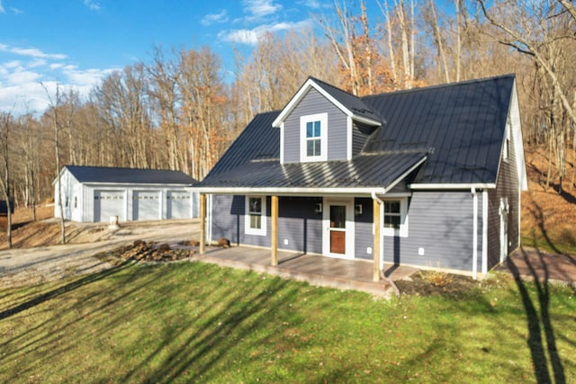 rear view of house with a porch, a garage, an outdoor structure, and a lawn