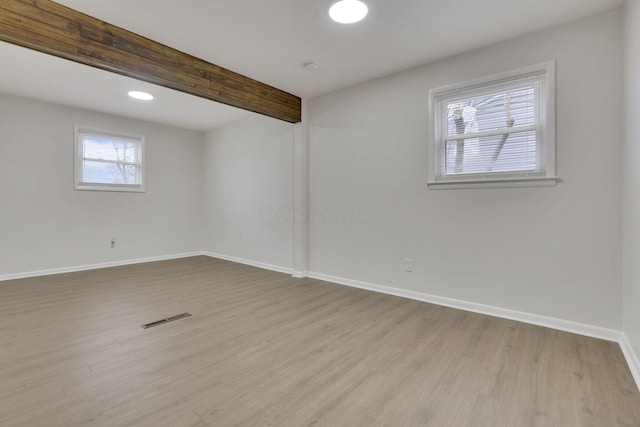 spare room with beamed ceiling and light hardwood / wood-style floors