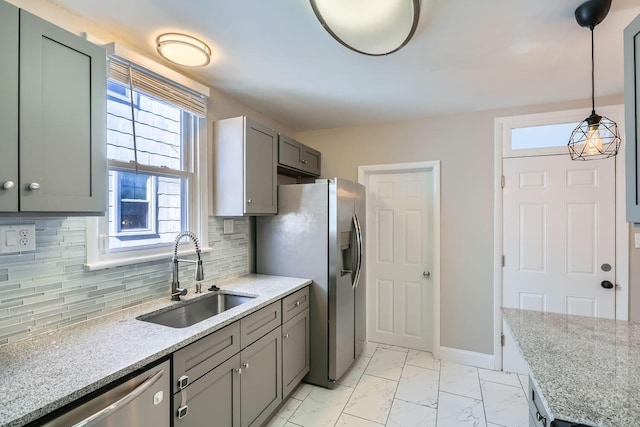 kitchen featuring appliances with stainless steel finishes, sink, backsplash, light stone counters, and pendant lighting