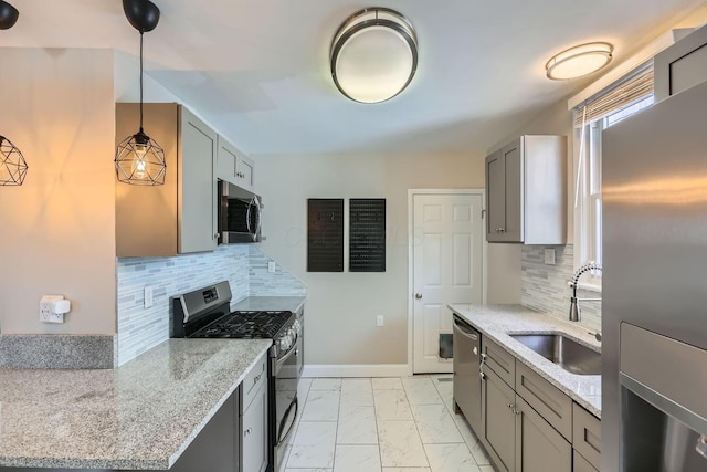 kitchen with sink, light stone countertops, stainless steel appliances, and pendant lighting