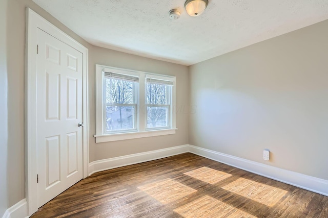 unfurnished room with a textured ceiling and dark hardwood / wood-style floors