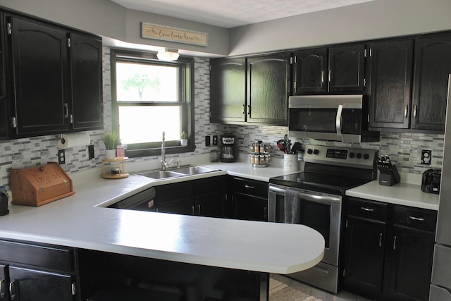 kitchen featuring tasteful backsplash, stainless steel appliances, kitchen peninsula, and sink