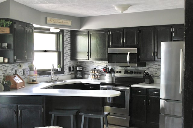 kitchen with tasteful backsplash, stainless steel appliances, sink, and a textured ceiling