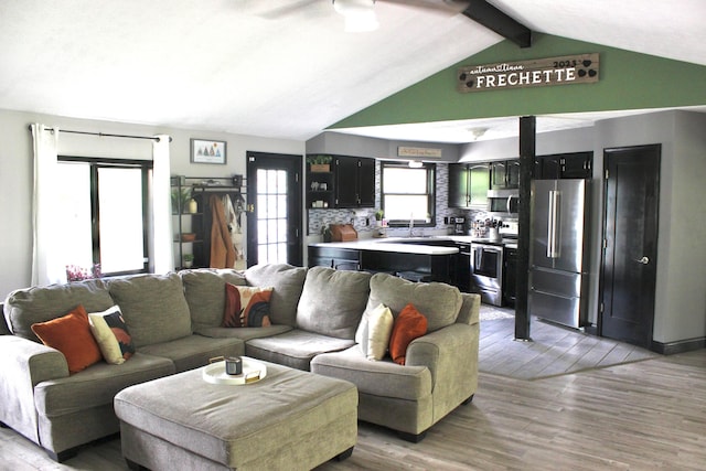 living room featuring lofted ceiling with beams, ceiling fan, sink, and light hardwood / wood-style floors