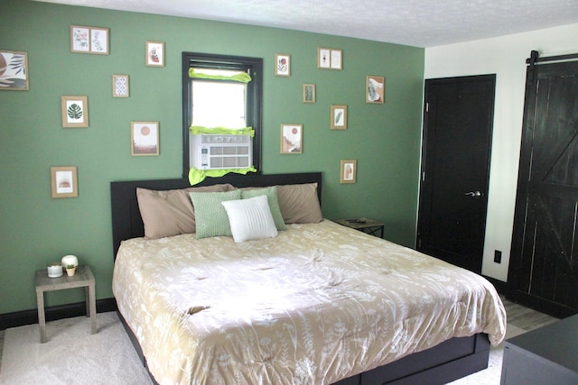 bedroom featuring cooling unit, a barn door, a textured ceiling, and carpet