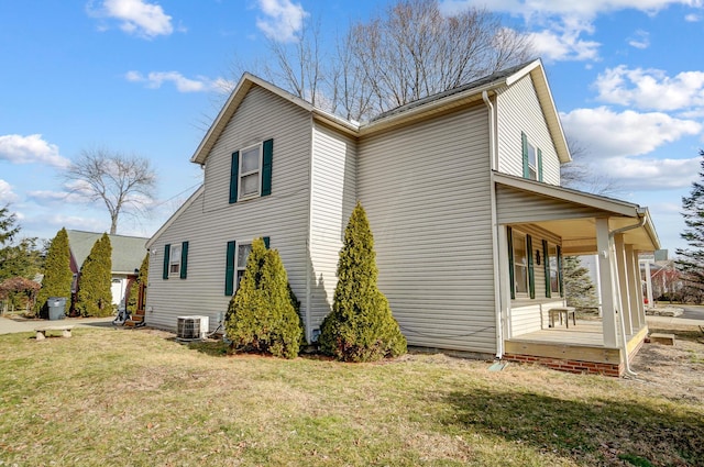 view of side of property featuring a yard, central AC unit, and covered porch