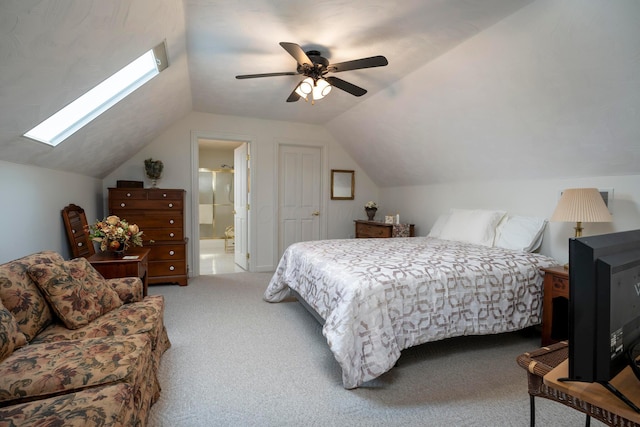 bedroom with ensuite bath, lofted ceiling with skylight, ceiling fan, and carpet flooring