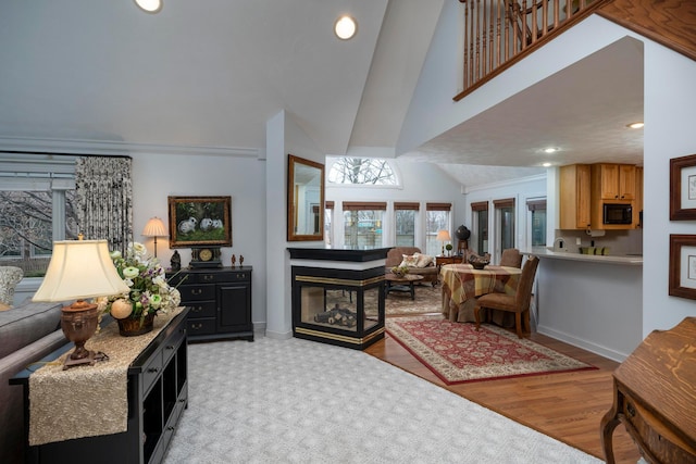 living room with a multi sided fireplace, crown molding, high vaulted ceiling, and light hardwood / wood-style floors