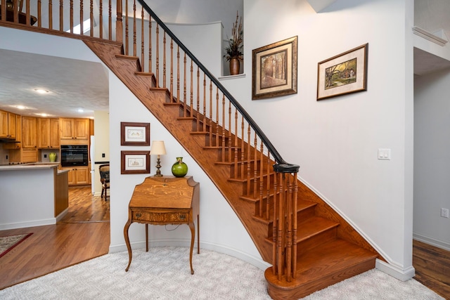 staircase featuring a high ceiling and wood-type flooring