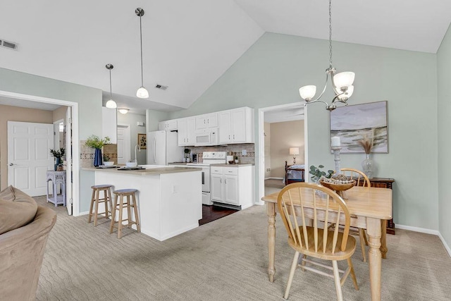 carpeted dining space featuring high vaulted ceiling, baseboards, visible vents, and a chandelier