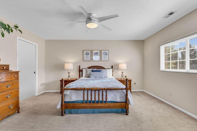 bedroom with a textured ceiling, baseboards, visible vents, and light carpet