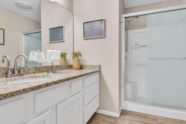 full bathroom with baseboards, vanity, wood finished floors, and a shower stall