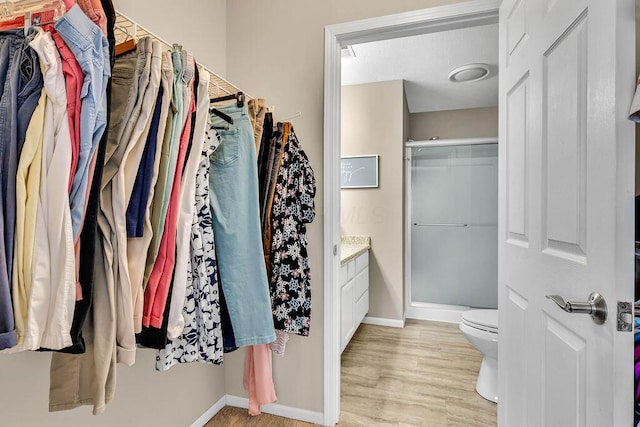 bathroom featuring toilet, wood finished floors, a shower stall, baseboards, and vanity