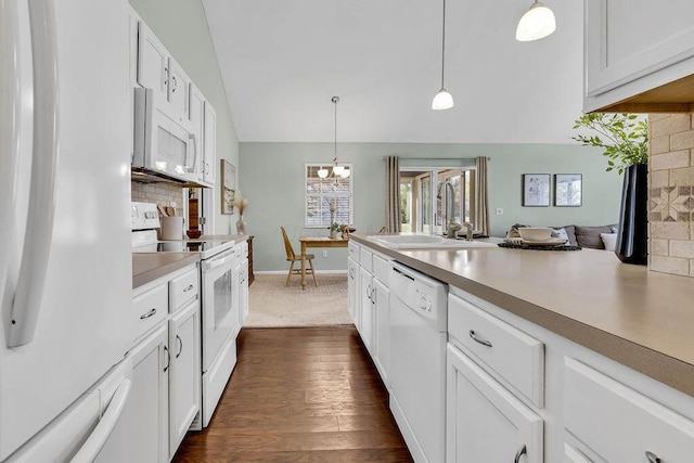 kitchen with white appliances, a sink, vaulted ceiling, decorative light fixtures, and tasteful backsplash