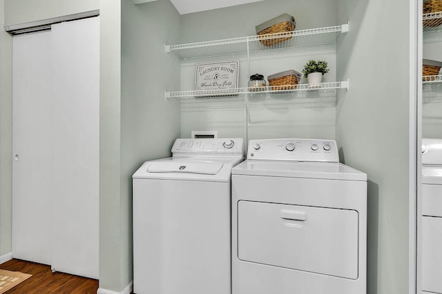 clothes washing area with baseboards, separate washer and dryer, wood finished floors, and laundry area