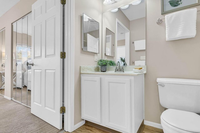 bathroom featuring toilet, vanity, and baseboards