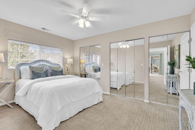 bedroom featuring light carpet, visible vents, multiple windows, and multiple closets