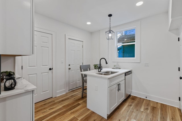 kitchen with sink, white cabinetry, light wood-type flooring, dishwasher, and pendant lighting