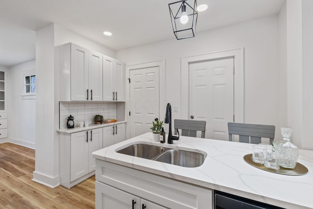 kitchen with tasteful backsplash, sink, white cabinets, and decorative light fixtures