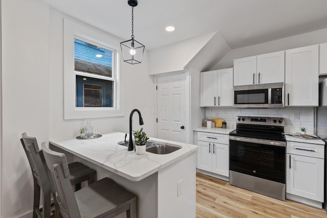 kitchen featuring appliances with stainless steel finishes, pendant lighting, sink, white cabinets, and light stone counters