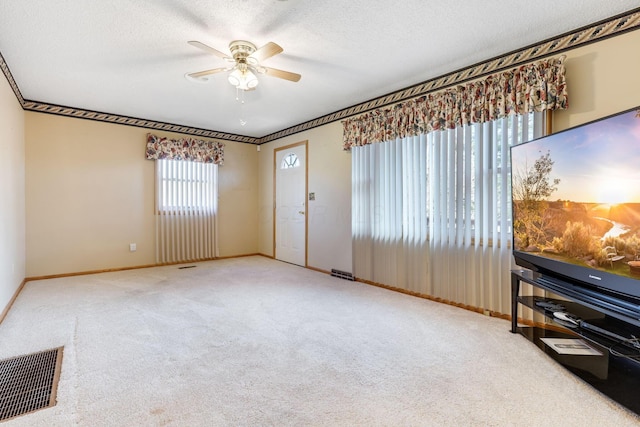 interior space featuring ceiling fan, light colored carpet, and a textured ceiling