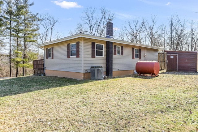 rear view of house with a shed, a lawn, central air condition unit, and a deck