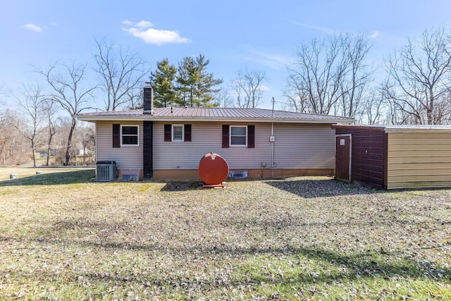 back of property with central AC unit and a yard