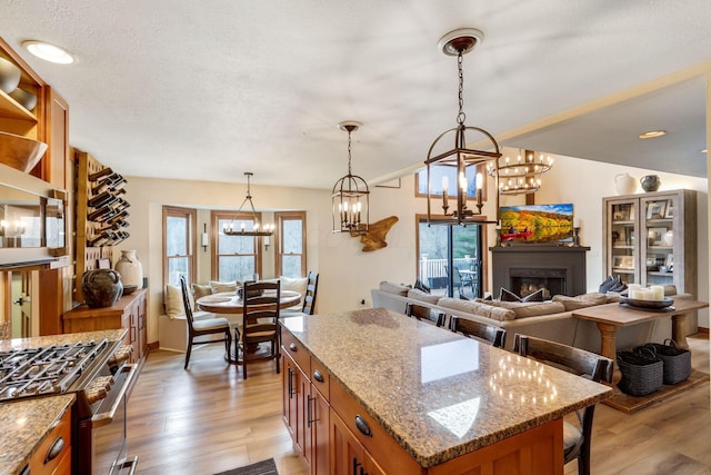 kitchen with light stone counters, appliances with stainless steel finishes, a center island, and hanging light fixtures