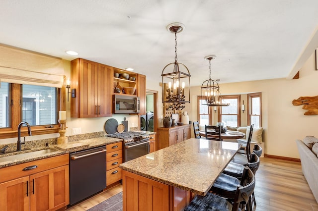 kitchen with a kitchen island, appliances with stainless steel finishes, separate washer and dryer, sink, and a breakfast bar area