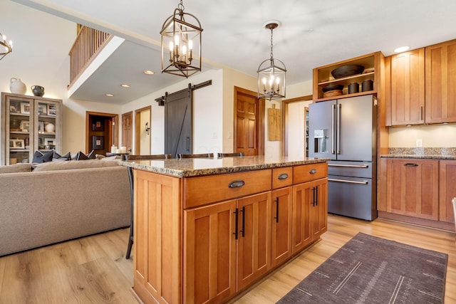 kitchen featuring high end fridge, hanging light fixtures, a barn door, and a kitchen island