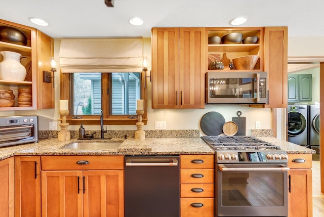 kitchen with light stone counters, washing machine and clothes dryer, stainless steel appliances, and sink