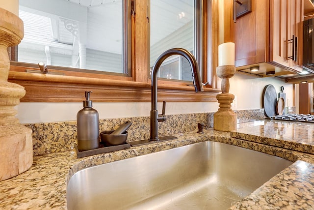 interior details featuring sink and light stone countertops