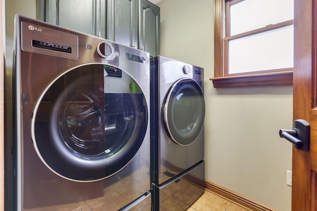 washroom featuring cabinets, light tile patterned floors, and washer and dryer