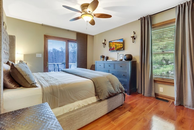 bedroom featuring hardwood / wood-style flooring, ceiling fan, access to exterior, and multiple windows