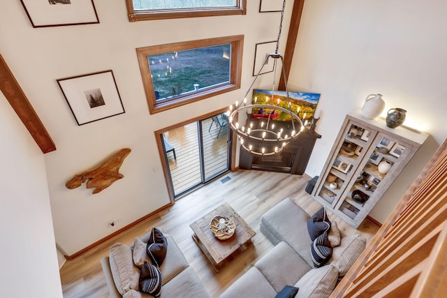 living room featuring plenty of natural light, a towering ceiling, a chandelier, and light hardwood / wood-style flooring