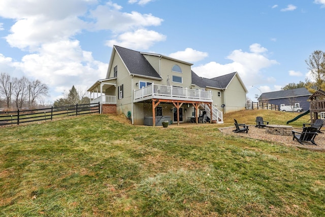 rear view of house featuring a fire pit, a lawn, and a deck