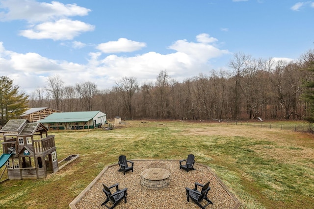 view of yard featuring a playground, a rural view, and a fire pit