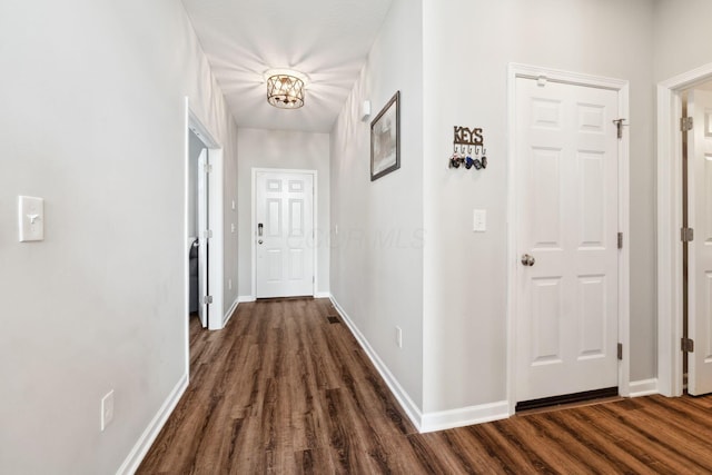 hall with an inviting chandelier, baseboards, and dark wood finished floors