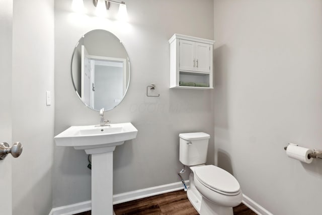 half bath with wood finished floors, toilet, and baseboards