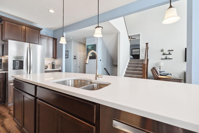 kitchen with light countertops, a sink, decorative light fixtures, and dark brown cabinetry