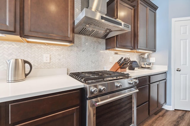 kitchen with dark brown cabinets, high end range, and wall chimney exhaust hood