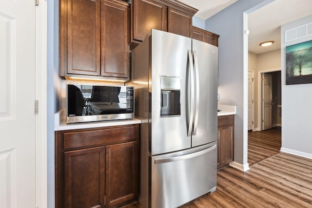 kitchen with light countertops, appliances with stainless steel finishes, wood finished floors, and visible vents