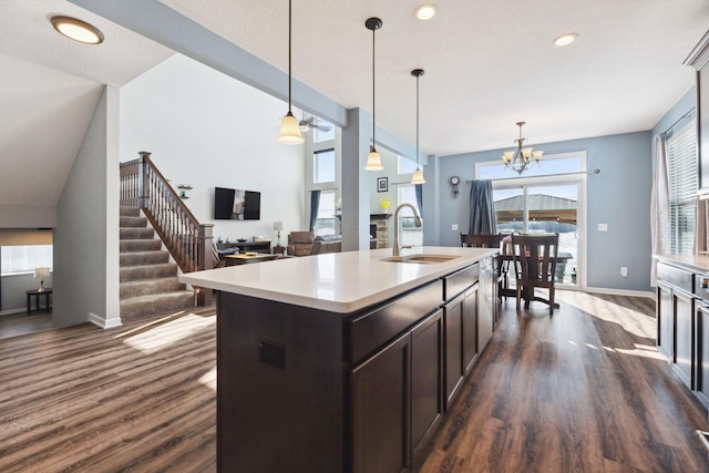 kitchen featuring dark wood-type flooring, a sink, baseboards, light countertops, and hanging light fixtures